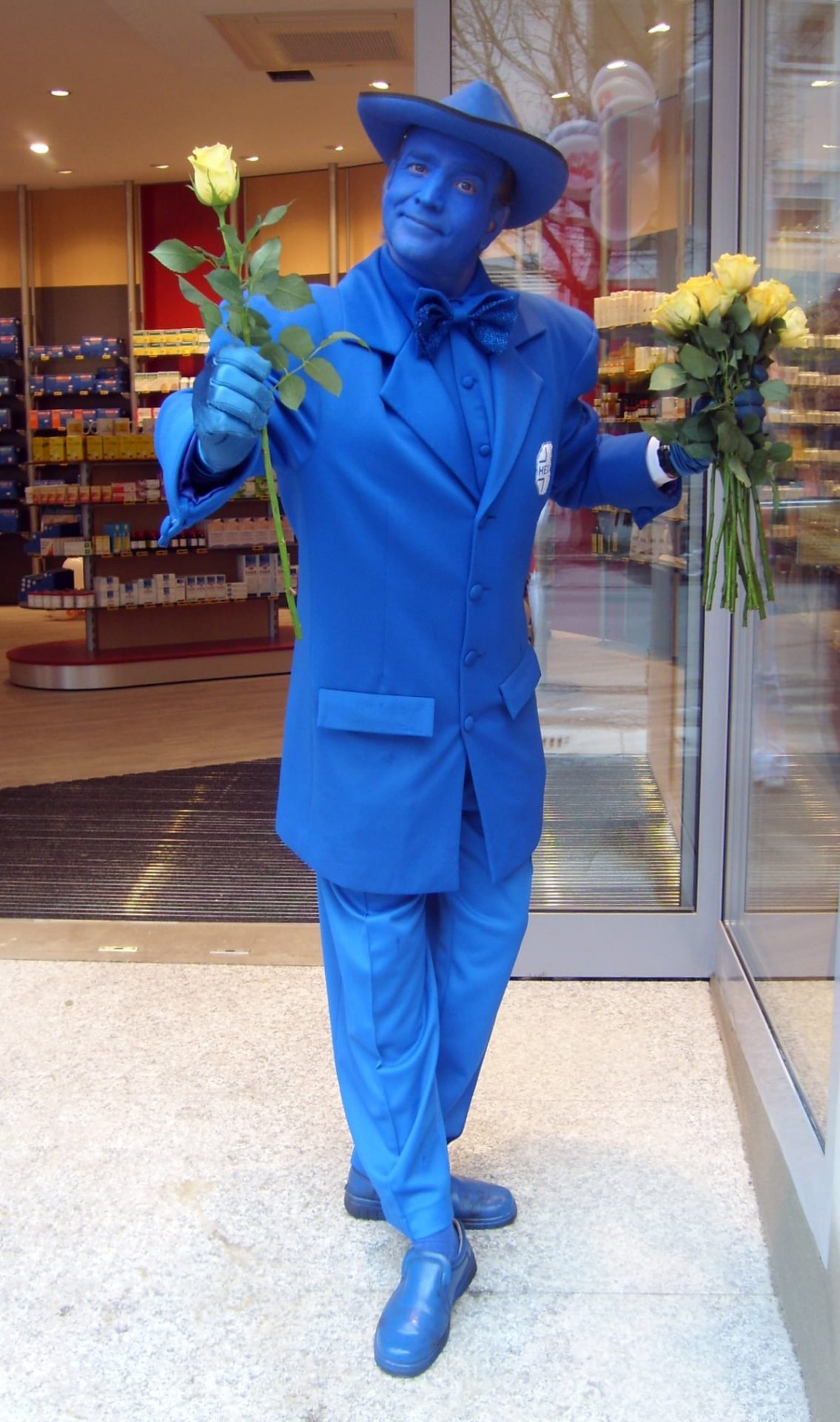 Blau gekleideter und geschminkter Begrüßer mit Rosen
